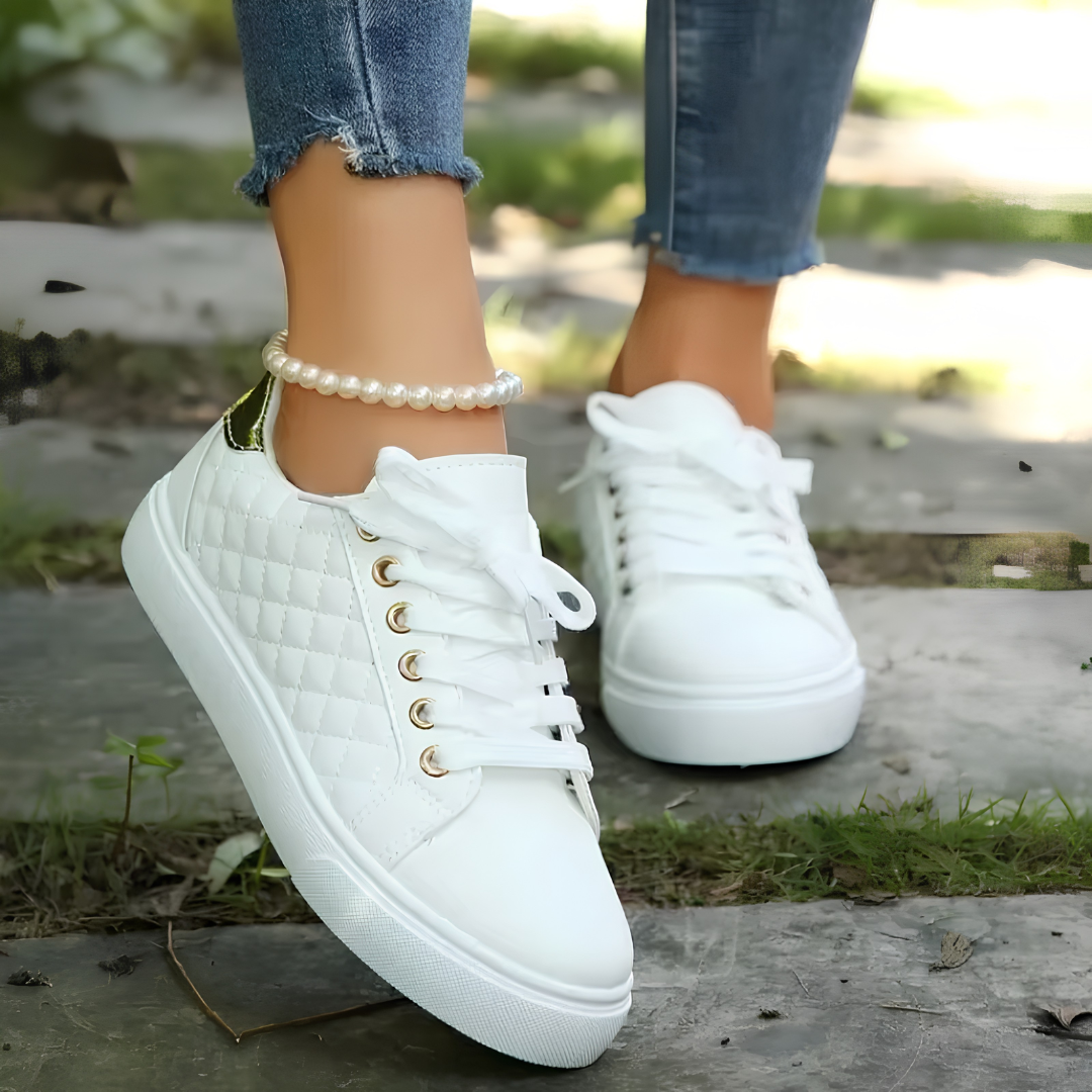 Sneakers blanches matelassées à lacets et détails dorés, vue de côté portées avec un jean