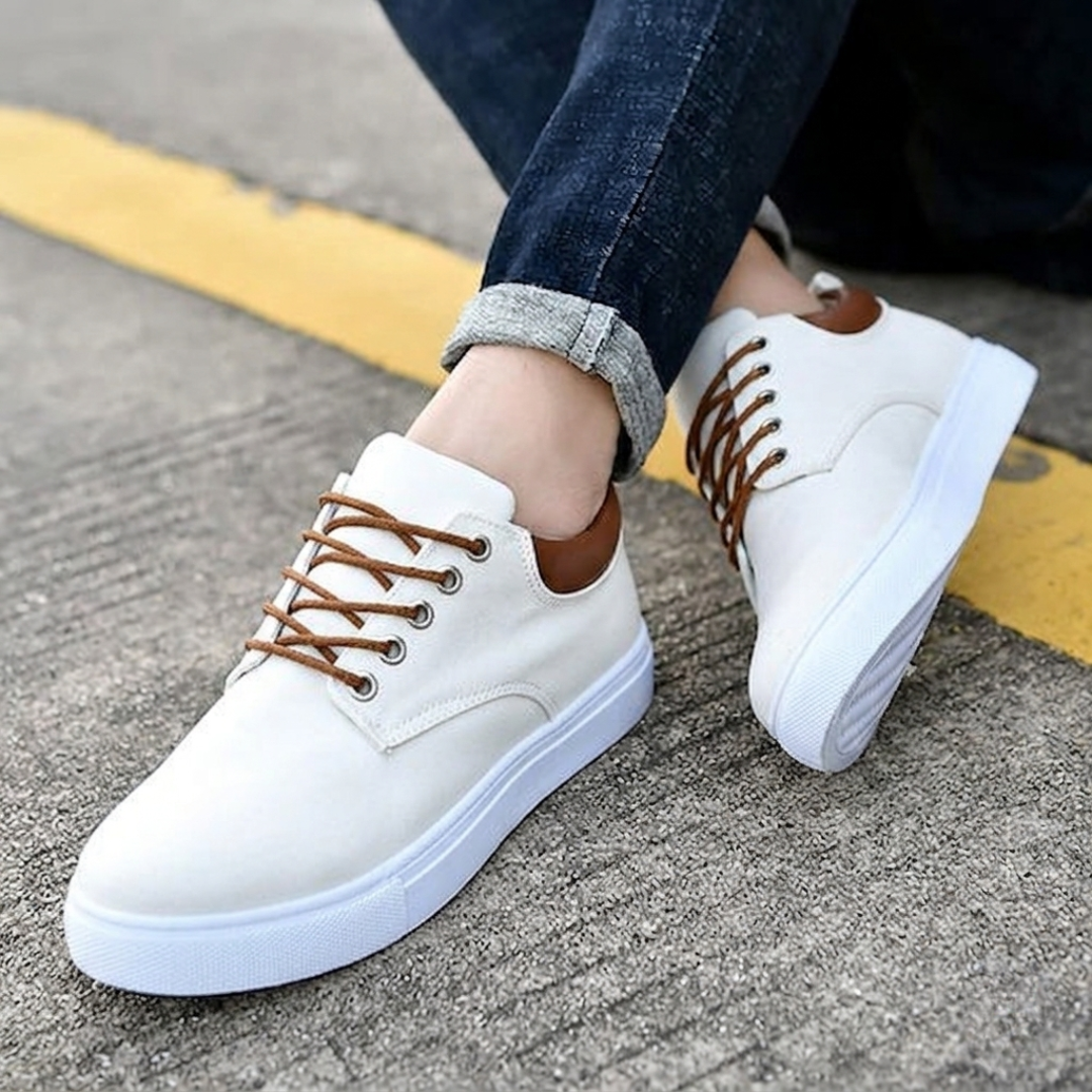 Sneakers blancs posés côte à côte, détail contrefort cognac