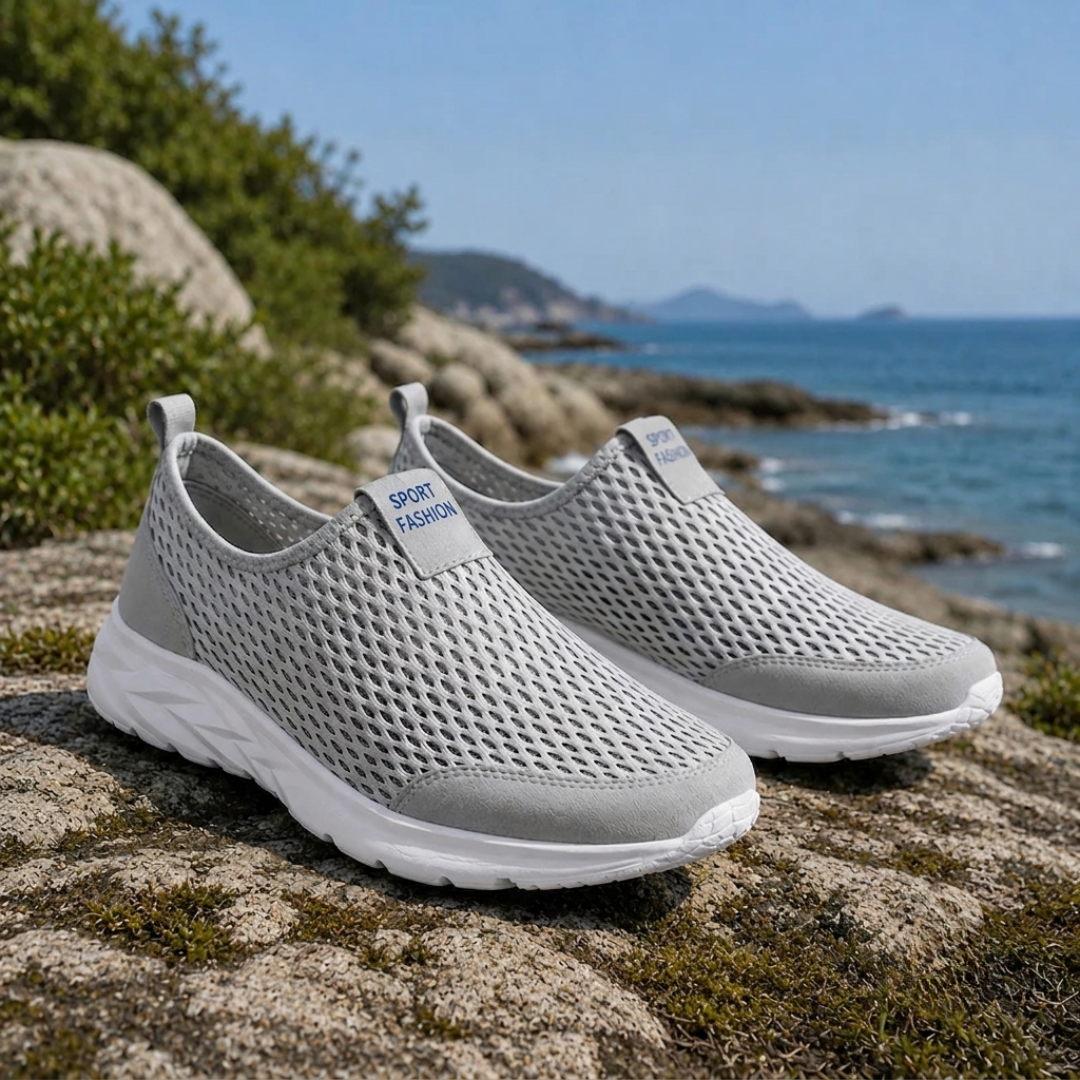 Paire de sneakers gris sans lacets en mesh posée sur des rochers au bord de la mer
