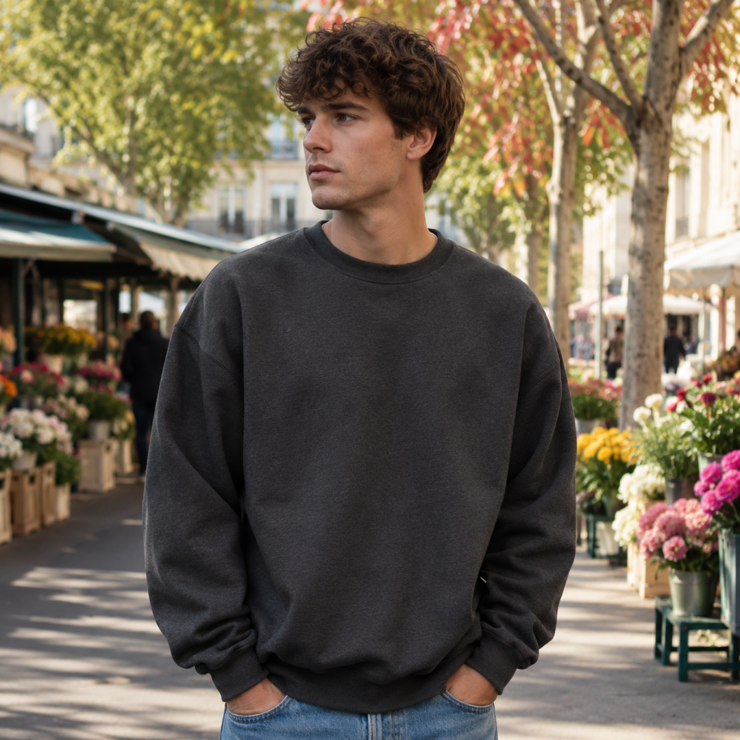 Sweat homme gris foncé à épaules tombantes et poignets côtelés devant un marché