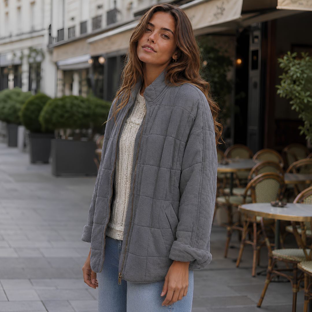 Veste matelassée gris foncé portée ouverte avec manches retroussées et pantalon clair