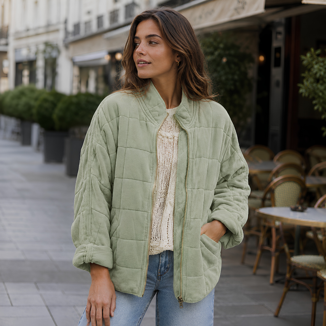 Veste matelassée verte à poches latérales, portée ouverte sur un pantalon clair