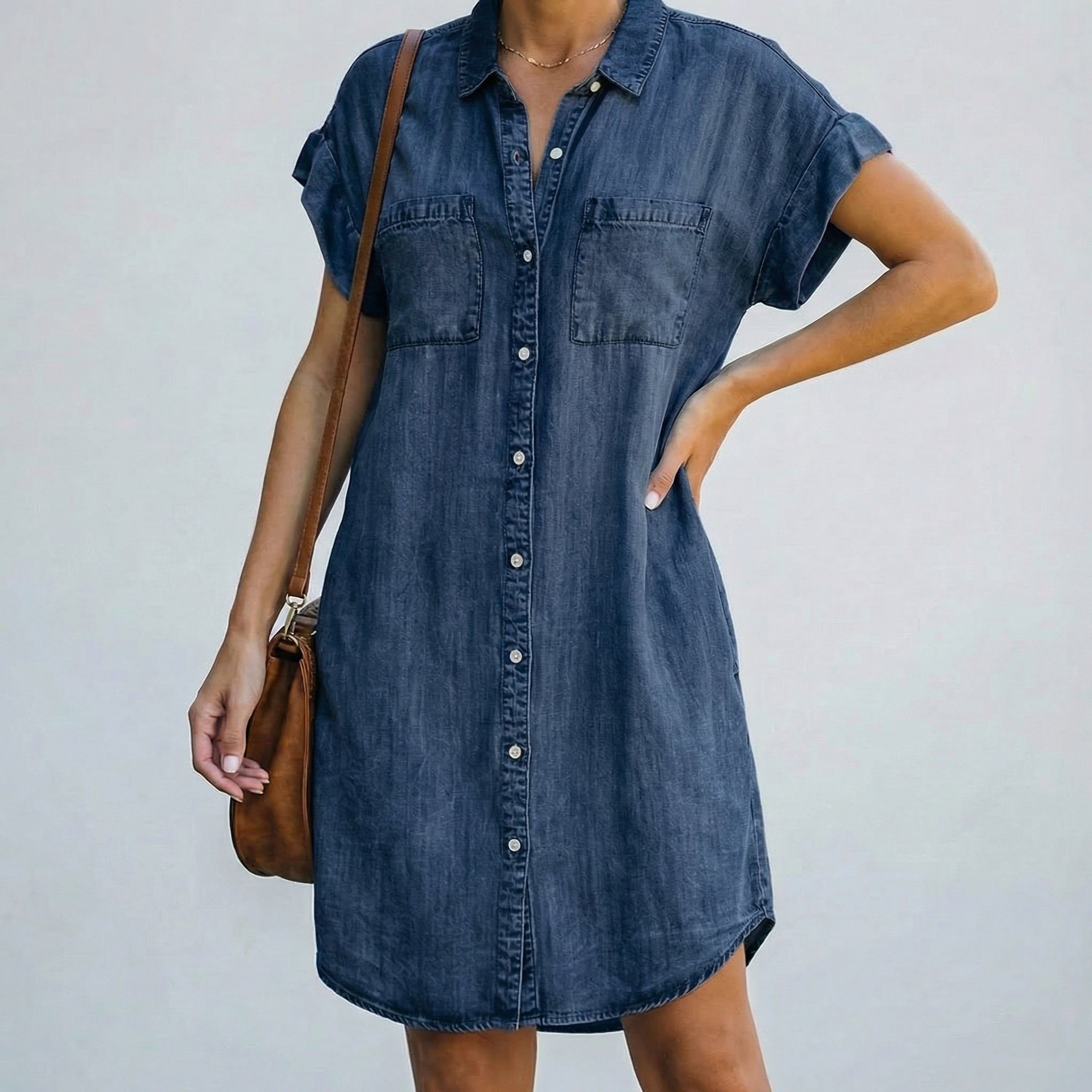 Robe chemise en jean bleu foncé, boutonnée sur le devant, à manches courtes retroussées et ourlet arrondi mi-long.
