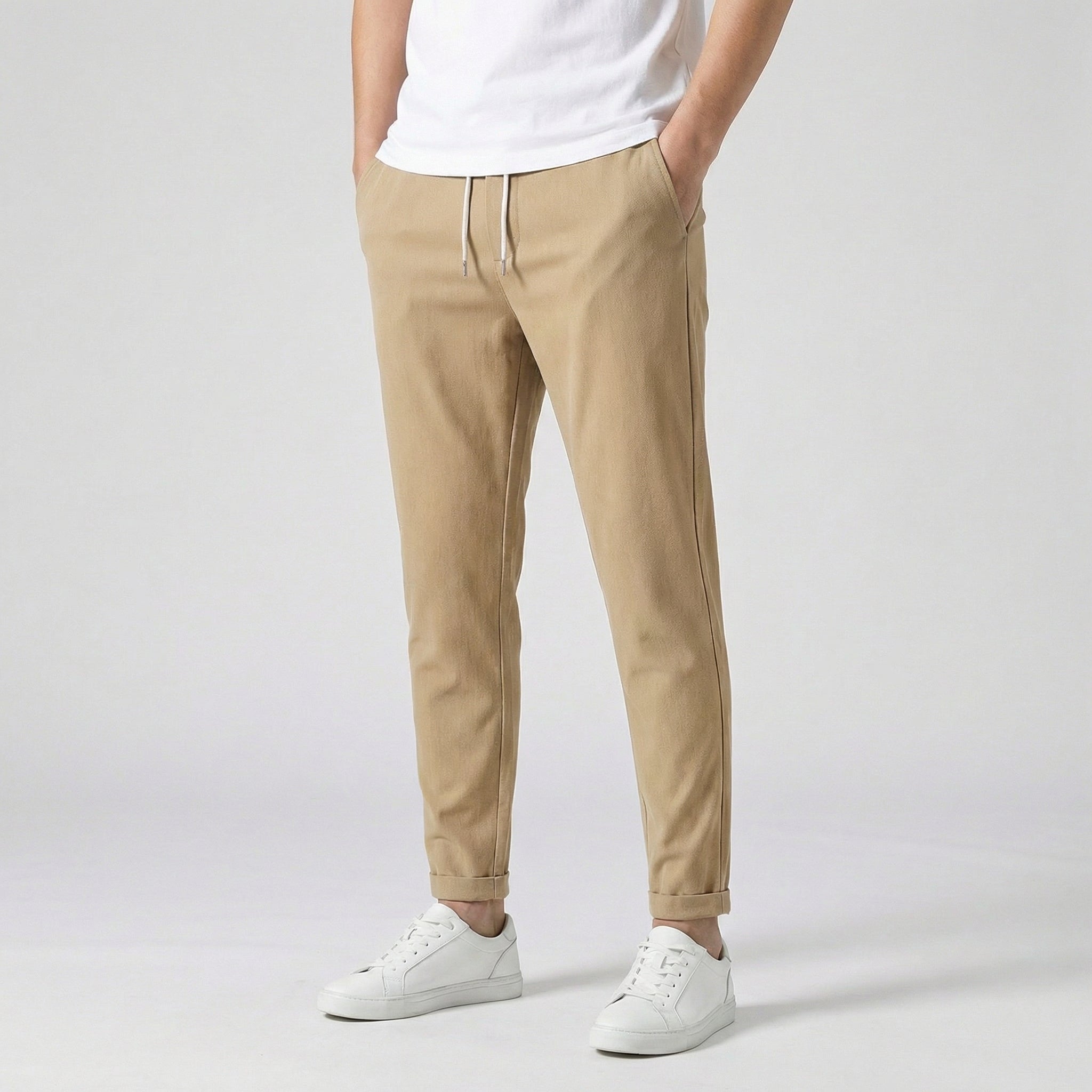 Pantalon jogger slim beige camel avec cordon de serrage, porté par un homme en t-shirt blanc et baskets blanches