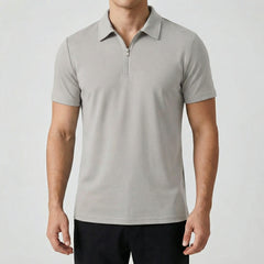 Polo zippé gris clair à manches courtes, fermeture éclair argentée, coupe slim, porté par un mannequin masculin, fond gris