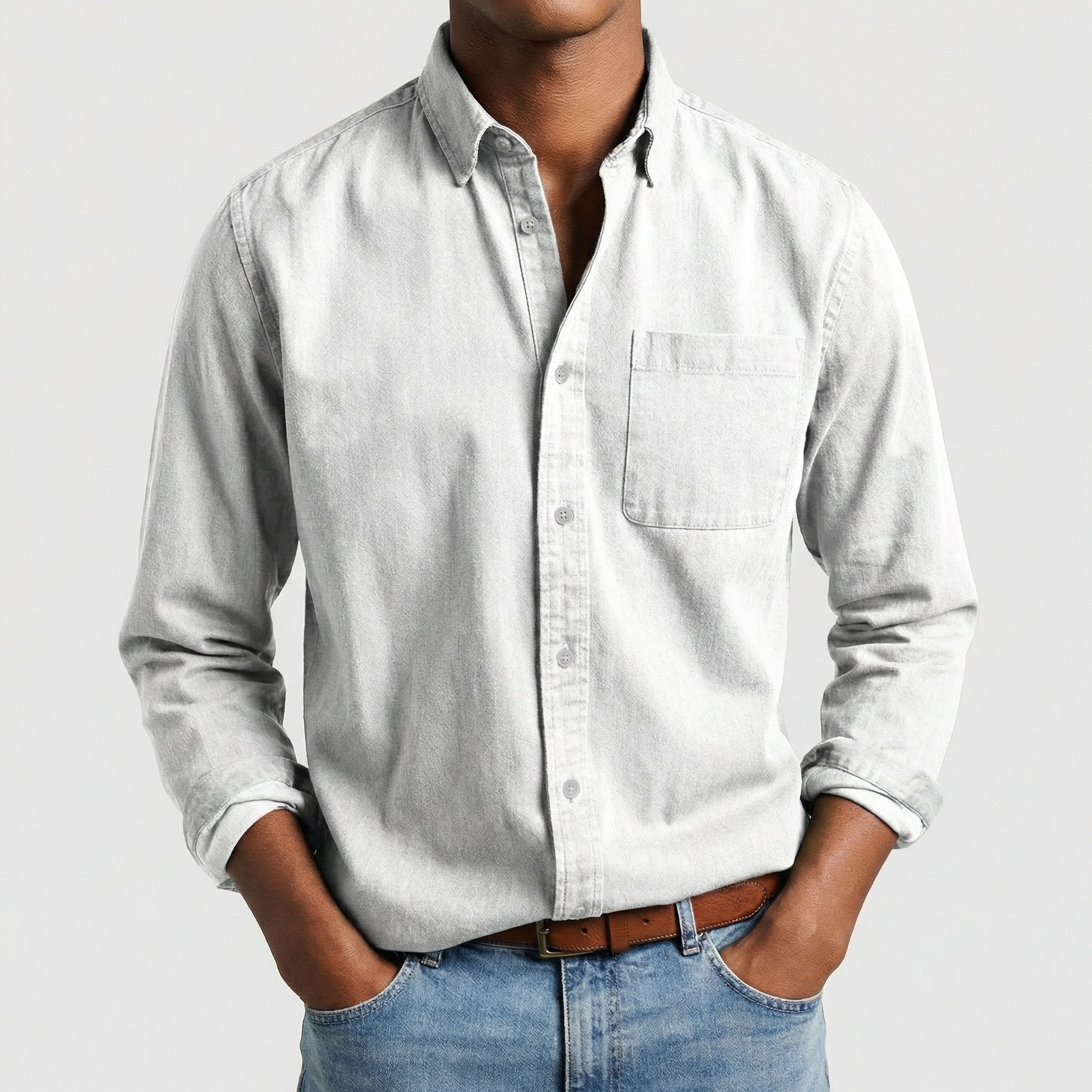 Chemise boutonnée manches longues en blanc, portée par un mannequin masculin sans visage visible, pose décontractée, fond gris clair
