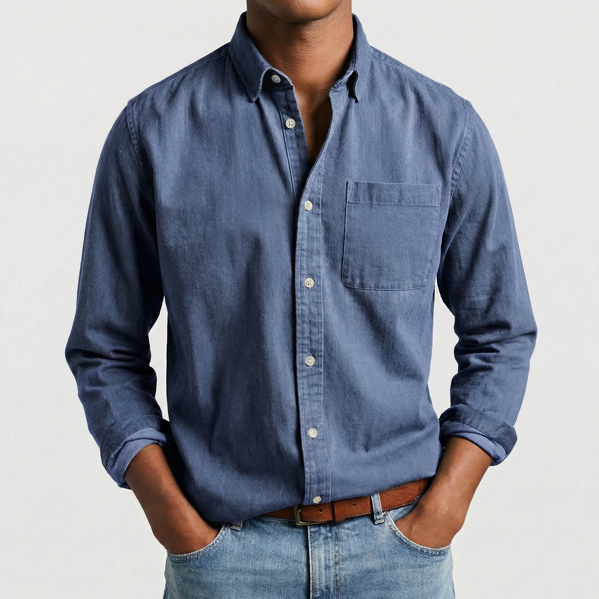 Chemise boutonnée manches longues en bleu, portée par un mannequin masculin sans visage visible, pose décontractée, fond gris clair