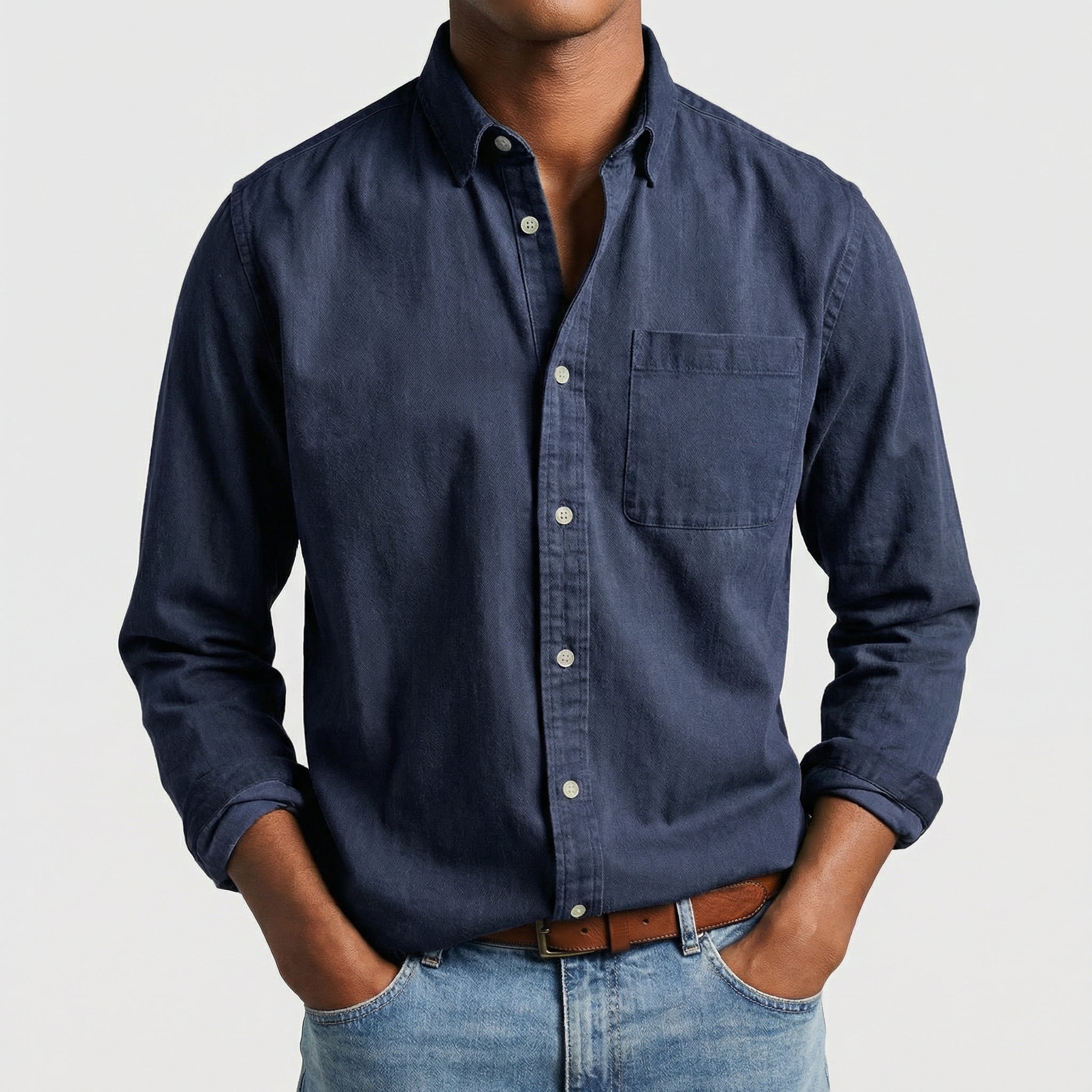 Chemise boutonnée manches longues en bleu marine, portée par un mannequin masculin sans visage visible, pose décontractée, fond gris clair