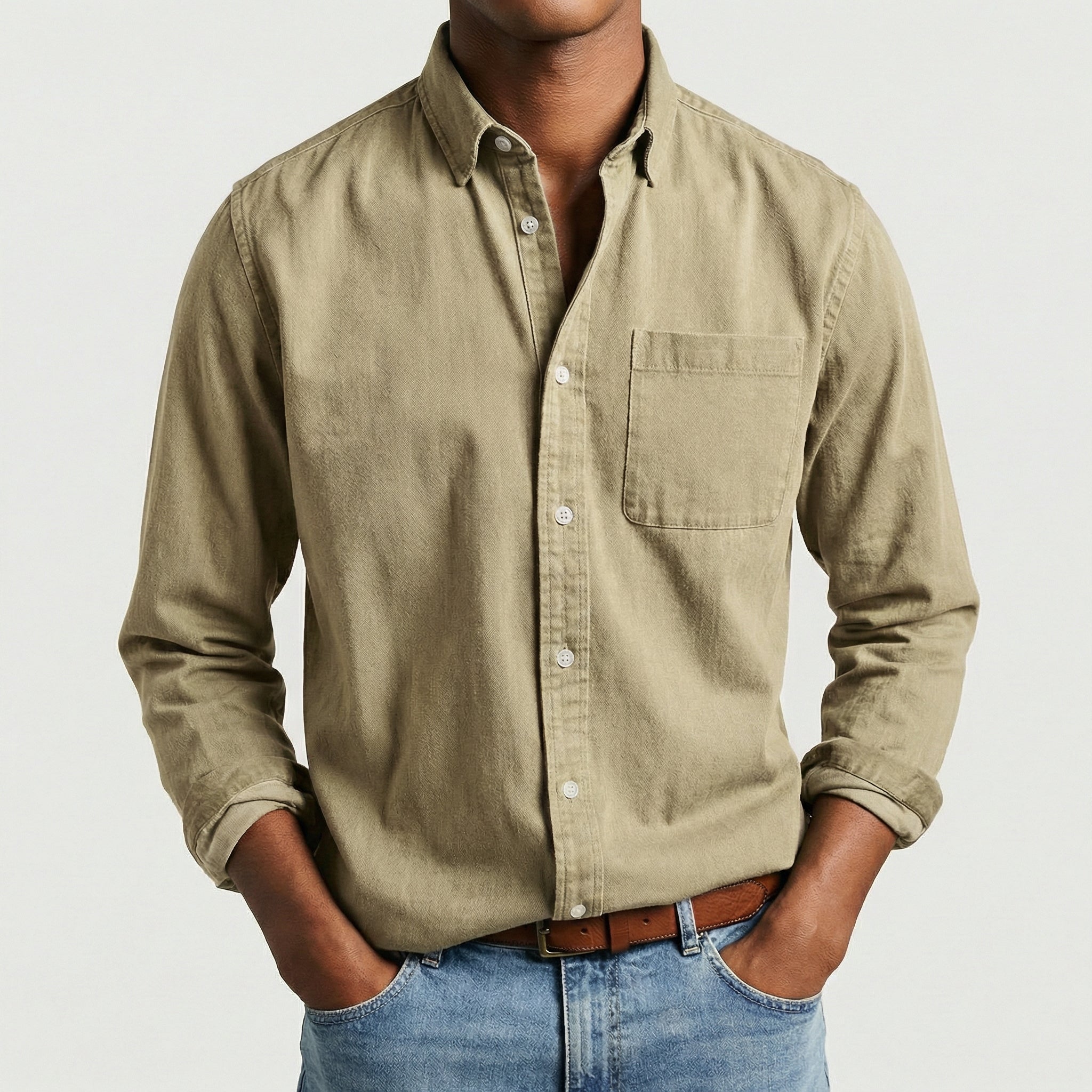 Chemise boutonnée manches longues en beige sable, portée par un mannequin masculin sans visage visible, pose décontractée, fond gris clair
