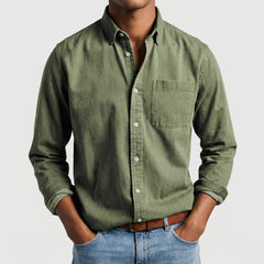 Chemise boutonnée manches longues en vert olive, portée par un mannequin masculin sans visage visible, pose décontractée, fond gris clair