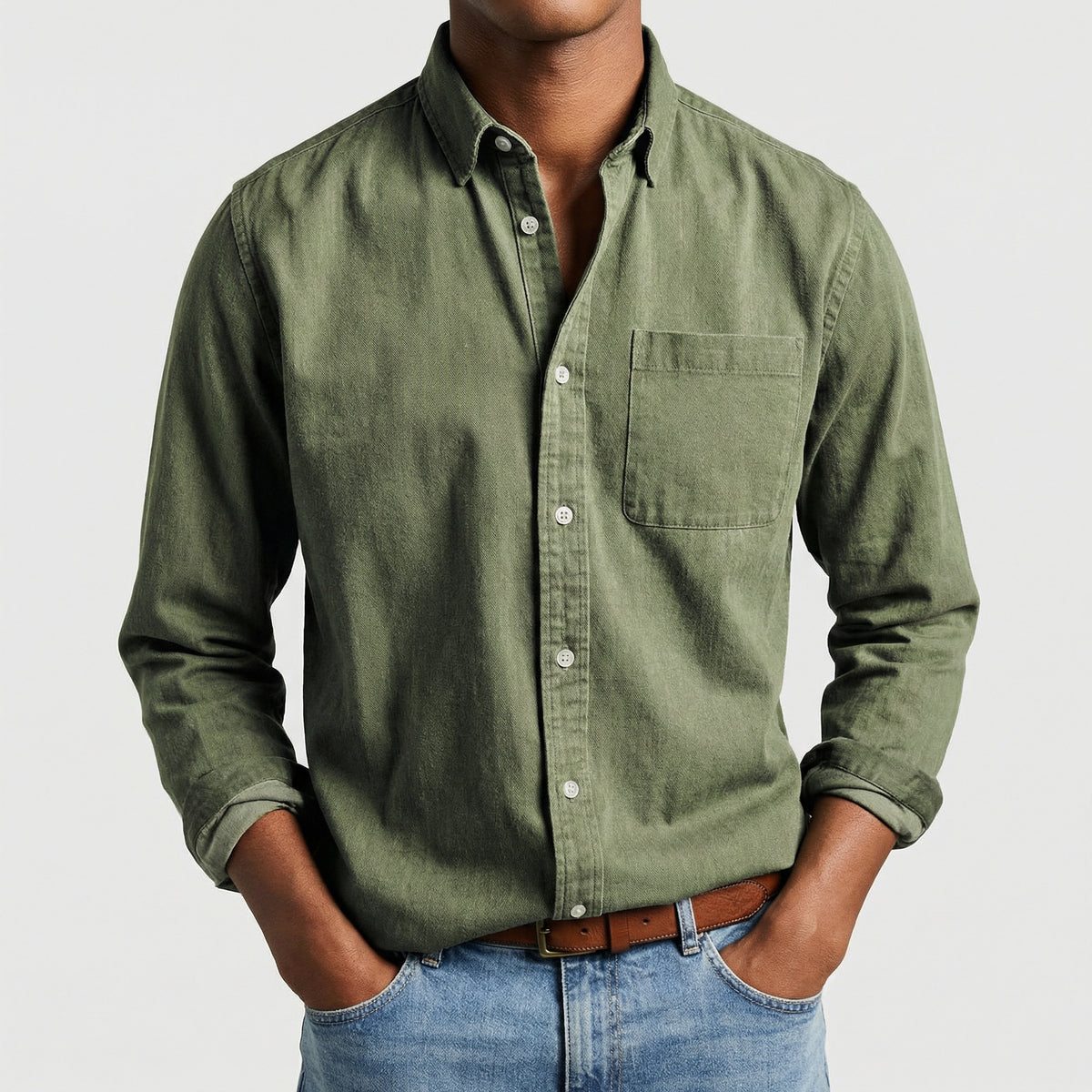 Chemise boutonnée manches longues en vert olive, portée par un mannequin masculin sans visage visible, pose décontractée, fond gris clair