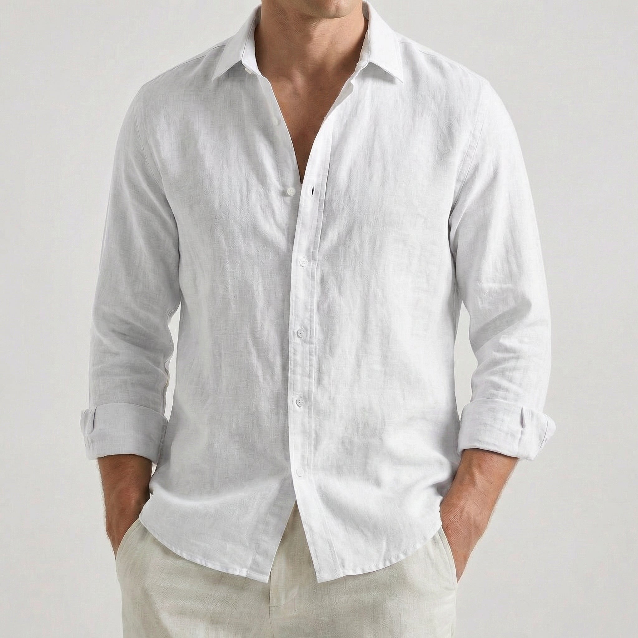 Chemise homme en lin à manches longues et col rabattu, coloris blanc, portée par un mannequin masculin dans une pose décontractée sur fond gris clair