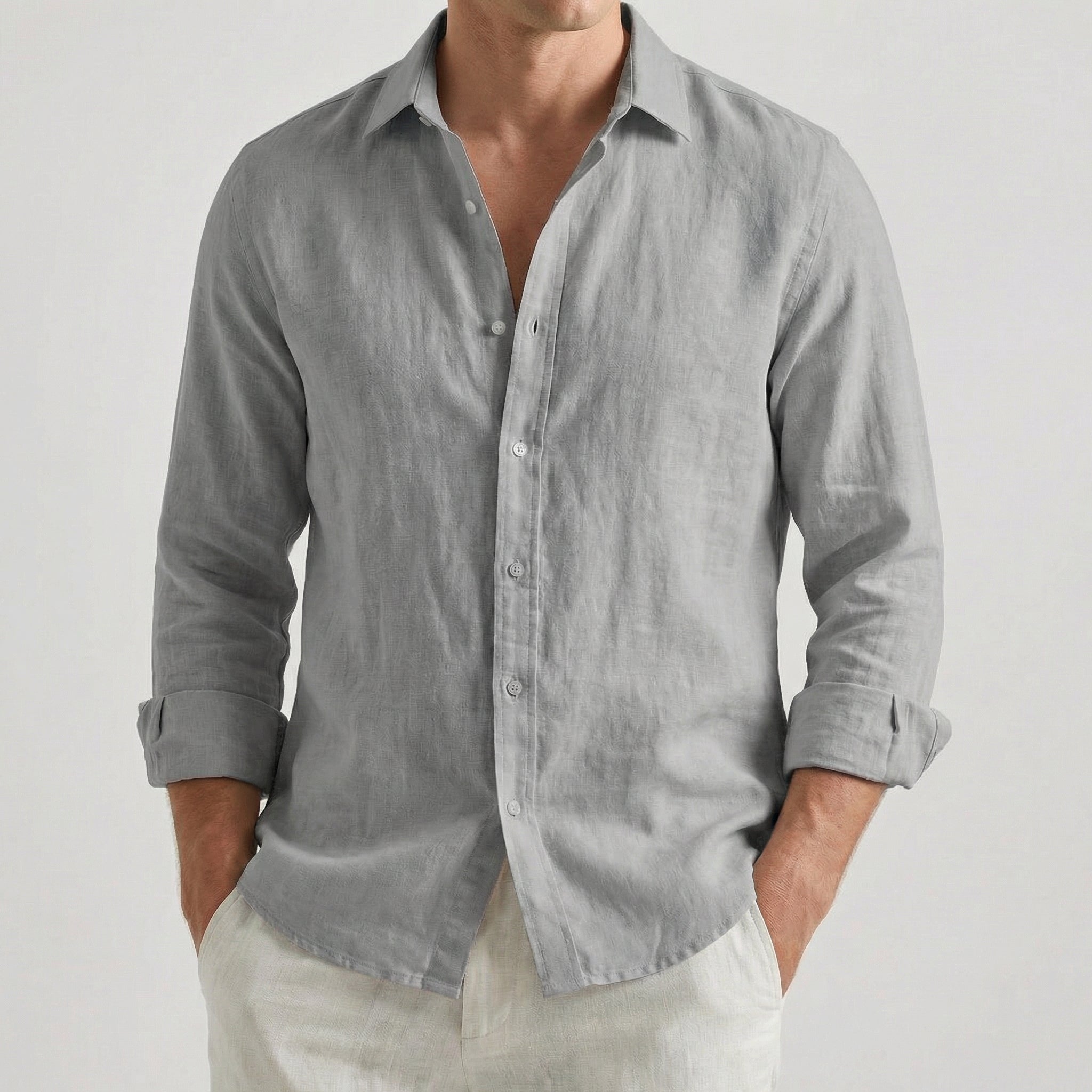 Chemise homme en lin à manches longues et col rabattu, coloris gris, portée par un mannequin masculin dans une pose décontractée sur fond gris clair