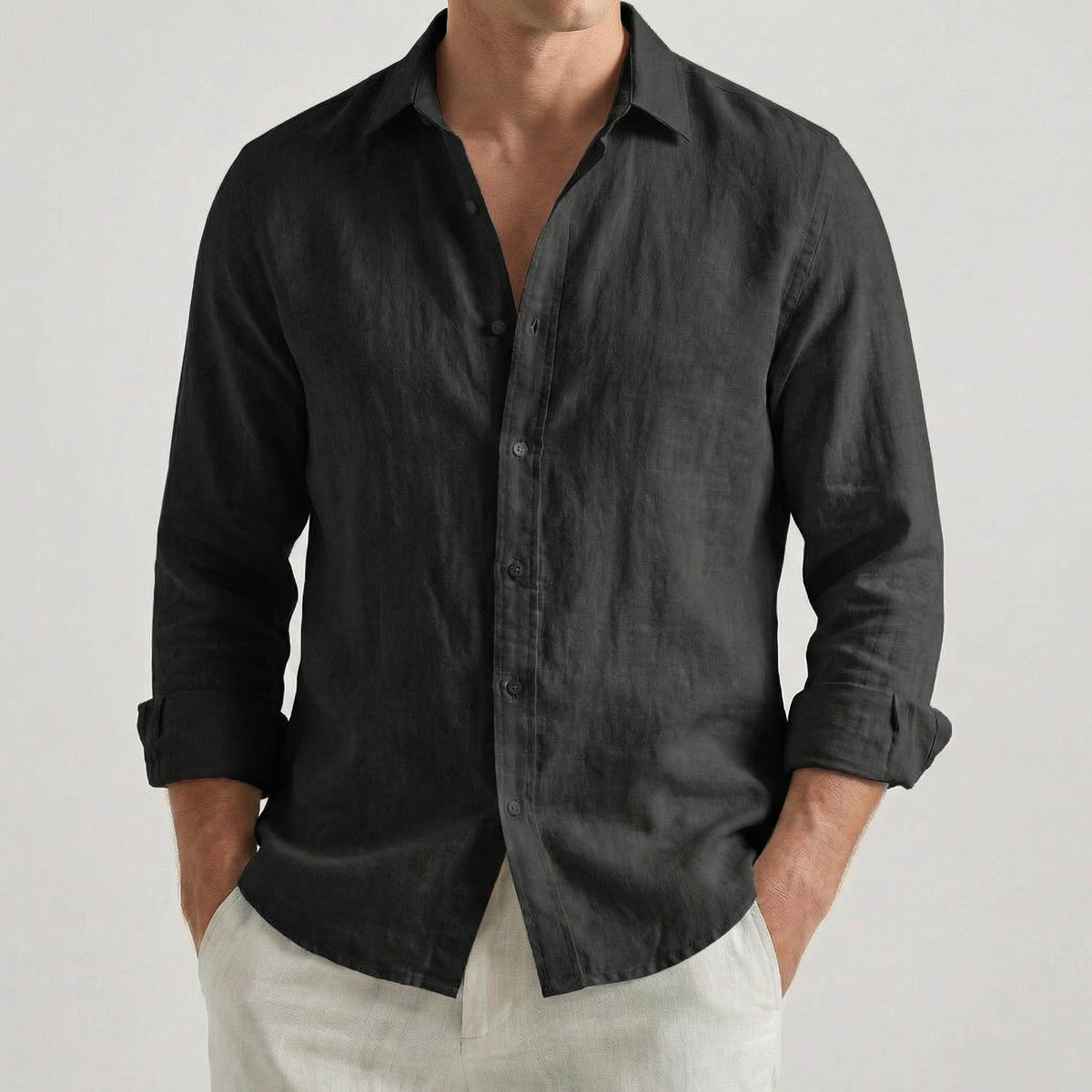 Chemise homme à manches longues et col rabattu, coloris noir, portée par un mannequin masculin dans une pose décontractée sur fond gris clair