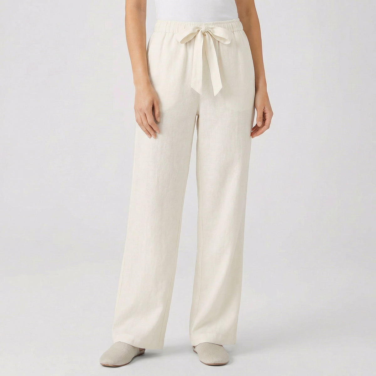 Pantalon fluide femme écru avec taille élastique et cordon, coupe droite, porté par mannequin, fond gris clair