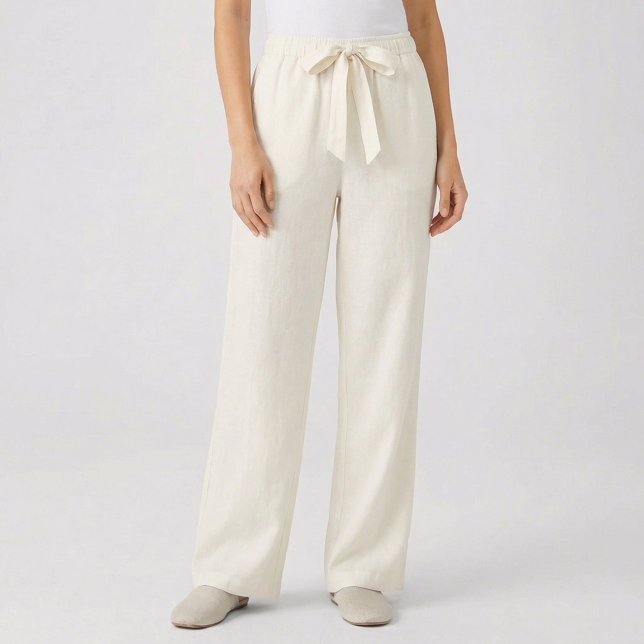 Pantalon fluide femme écru avec taille élastique et cordon, coupe droite, porté par mannequin, fond gris clair