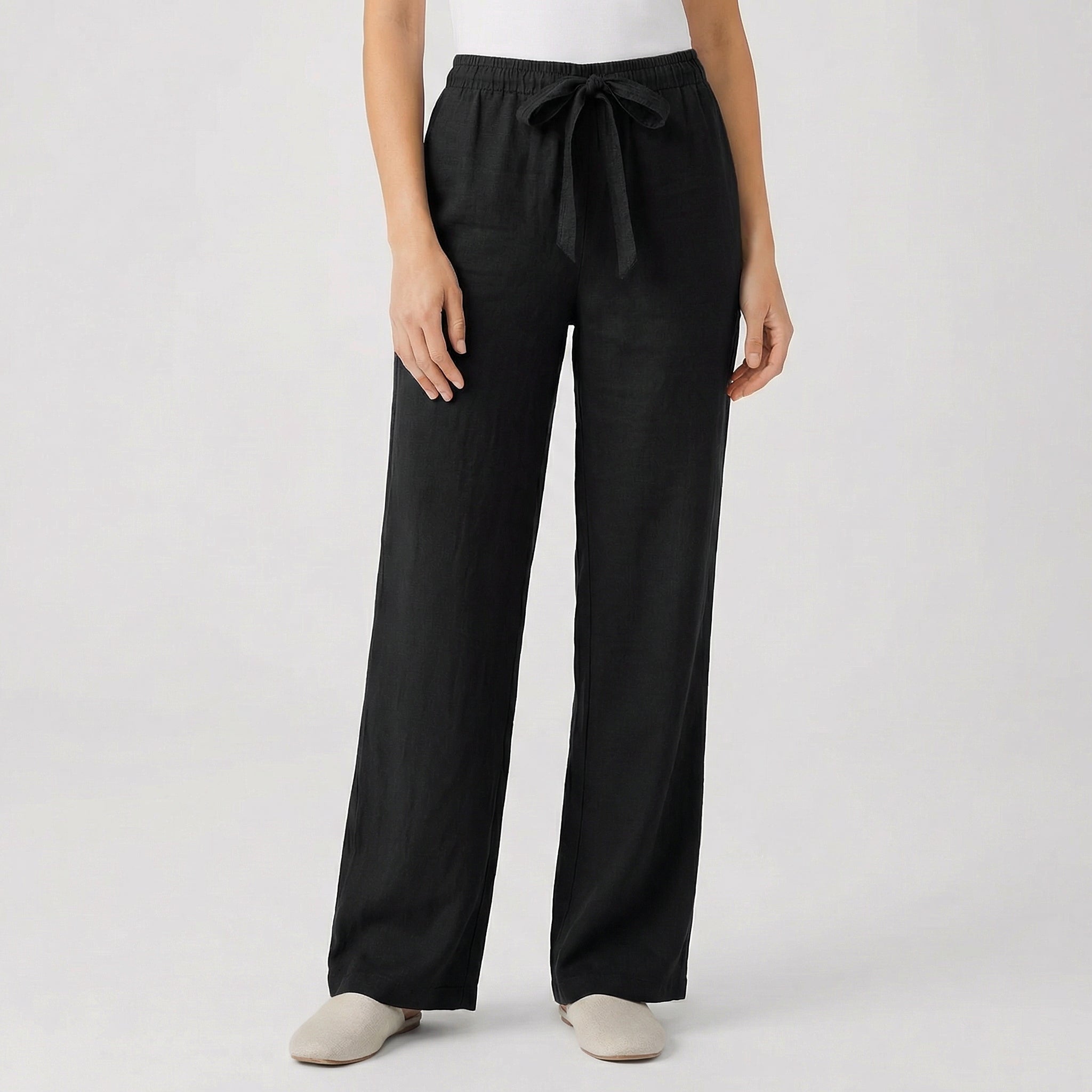 Pantalon fluide femme noir avec taille élastique et cordon, coupe droite, porté par mannequin, fond gris clair