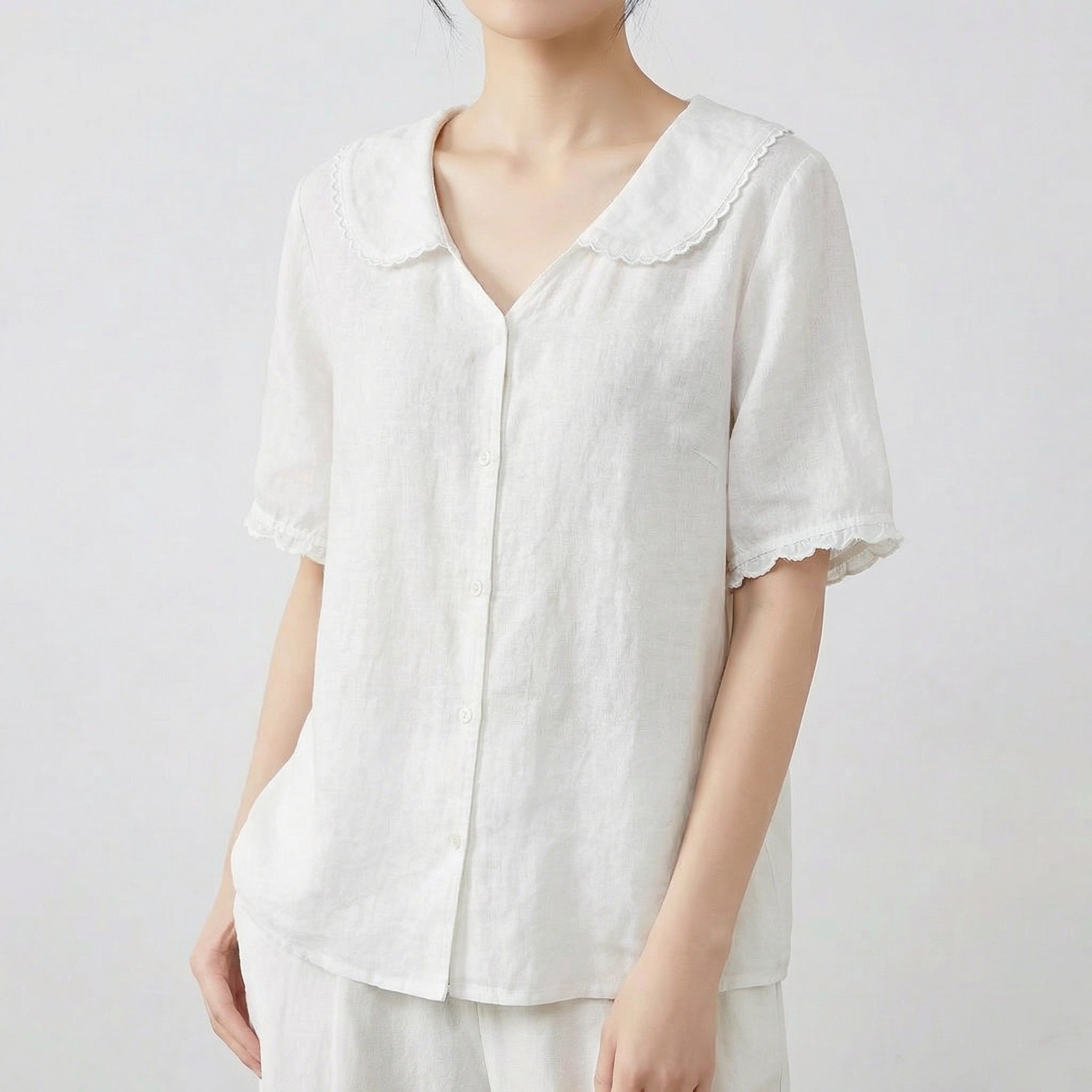 Chemise femme en lin à col chemisier et manches courtes en blanc cassé, portée avec un pantalon blanc