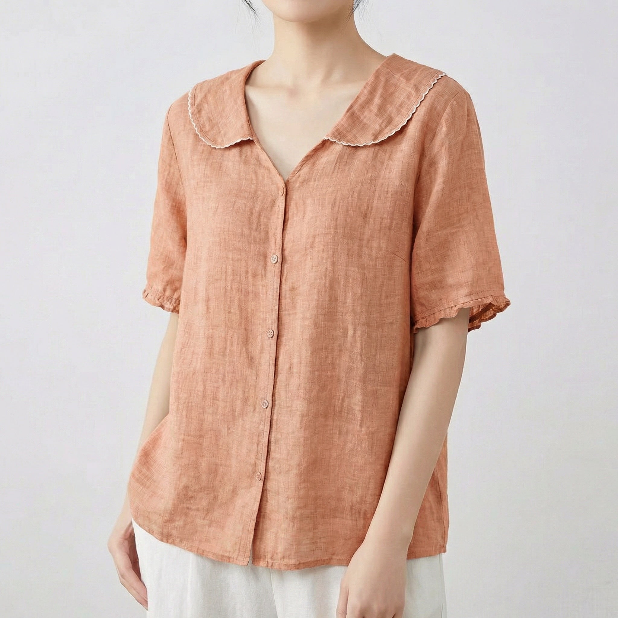Chemise femme en lin à col chemisier et manches courtes en terracotta saumon, portée avec un pantalon blanc