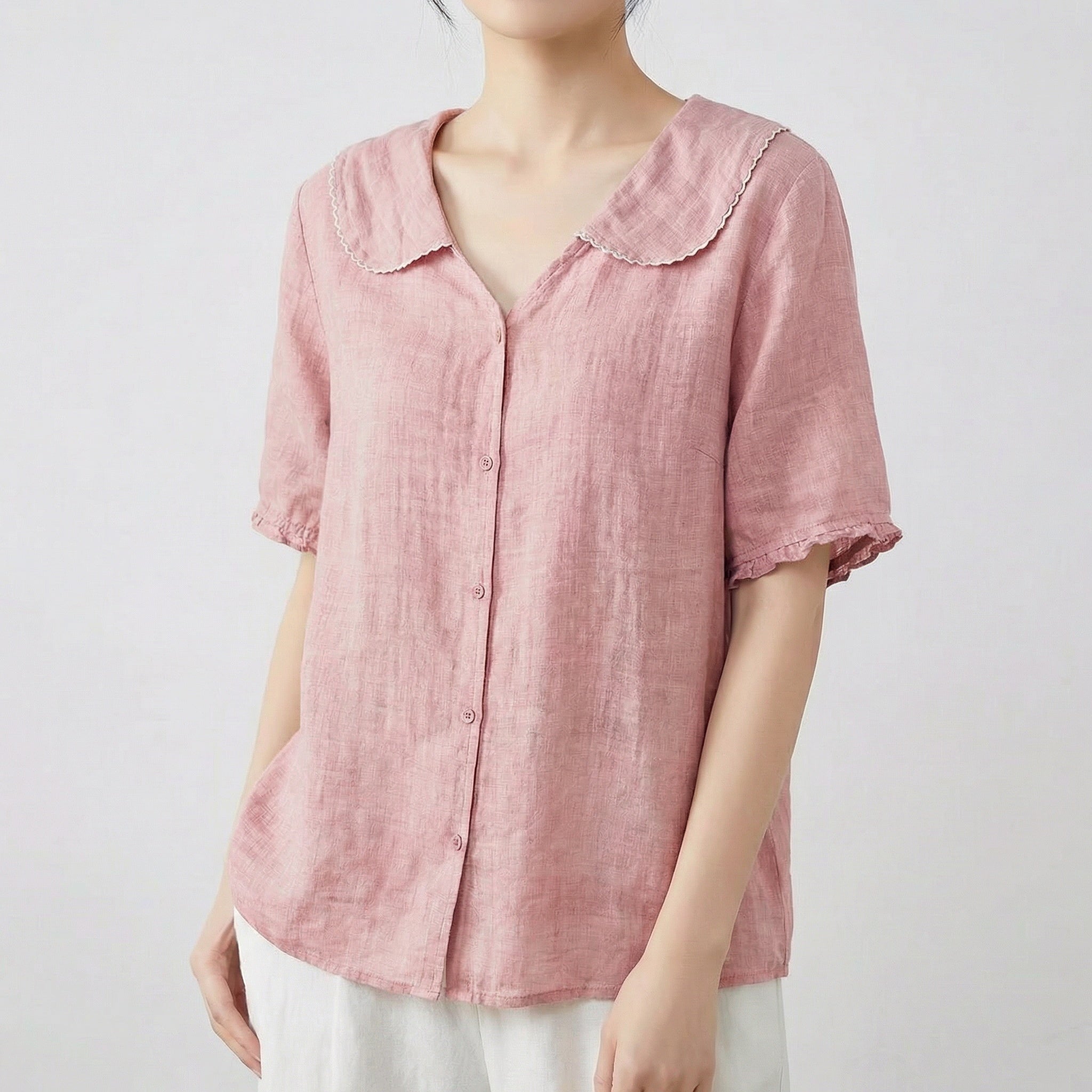 Chemise femme en lin à col chemisier et manches courtes en rose poudré, portée avec un pantalon blanc