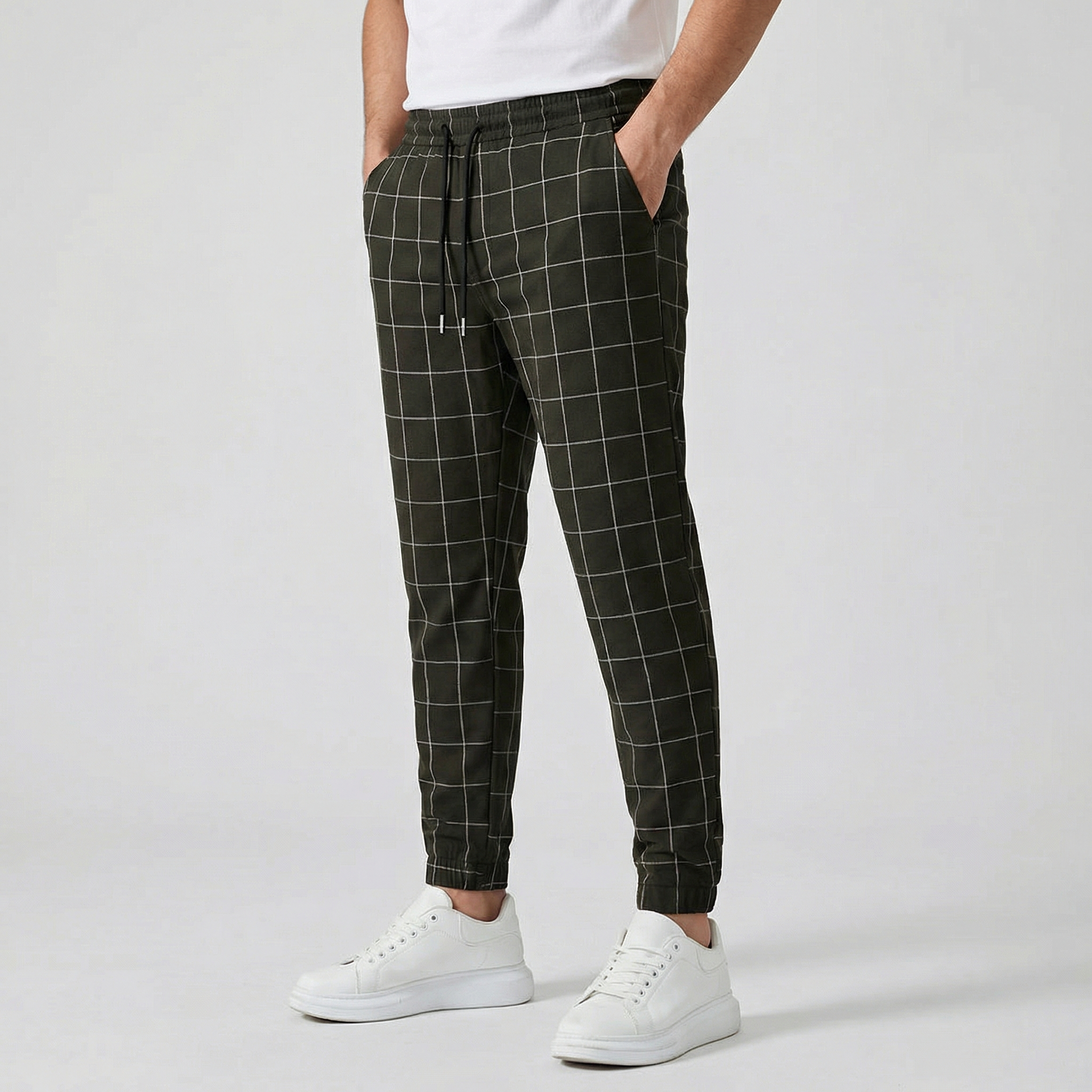 Pantalon jogger à carreaux pour homme, couleur noir, taille élastiquée avec cordon, poches latérales et chevilles côtelées, porté avec des baskets blanches