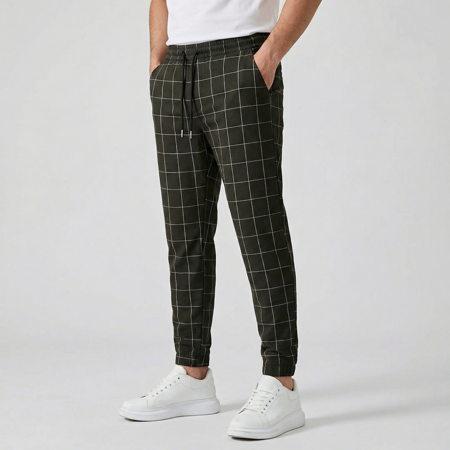 Pantalon jogger à carreaux pour homme, couleur noir, taille élastiquée avec cordon, poches latérales et chevilles côtelées, porté avec des baskets blanches