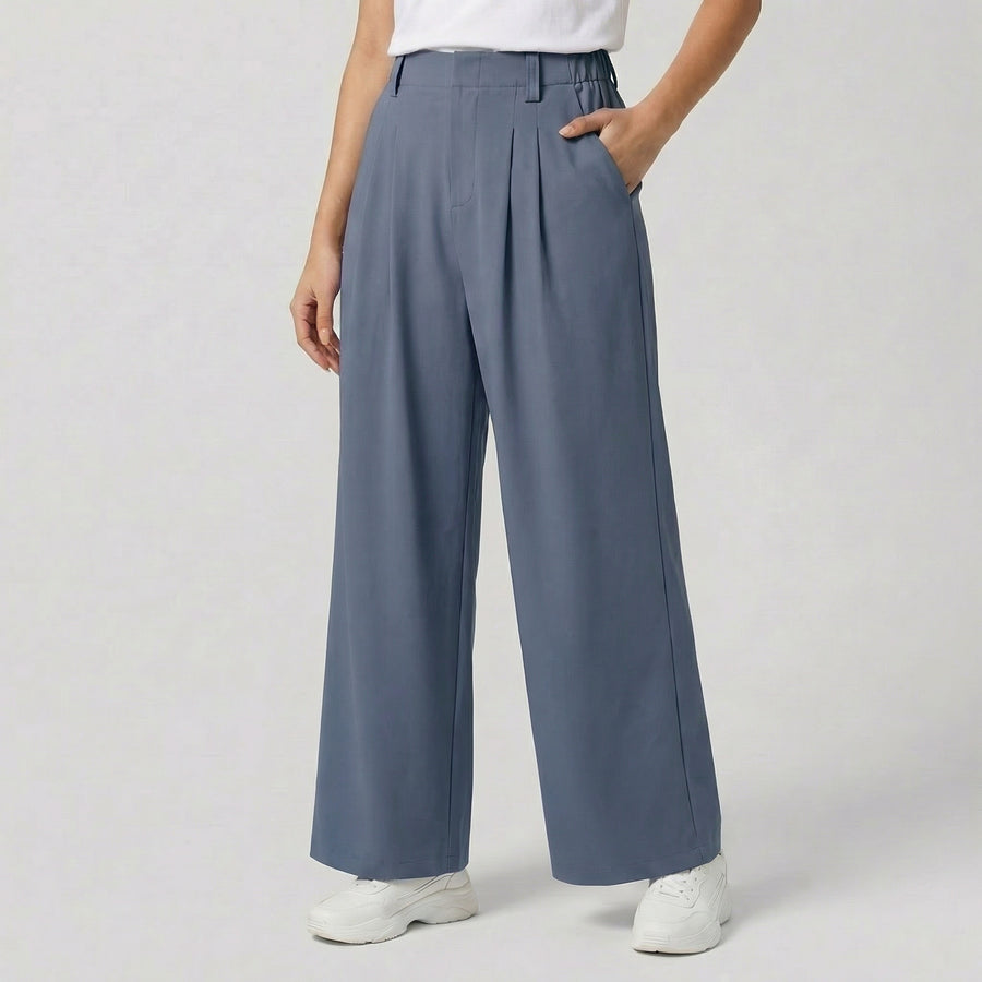 Pantalon large taille haute à plis plats, coloris bleu ardoise, avec ceinture élastiquée, poches latérales et jambes amples — coupe fluide et élégante