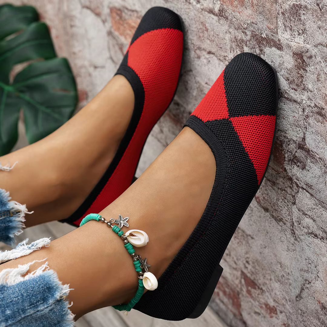 Ballerines plates rouges et noires portées près d'un mur, entrée échancrée et semelle fine