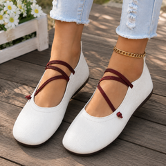 Ballerines plates blanches en gros plan, bout carré souple et brides élastiques croisées