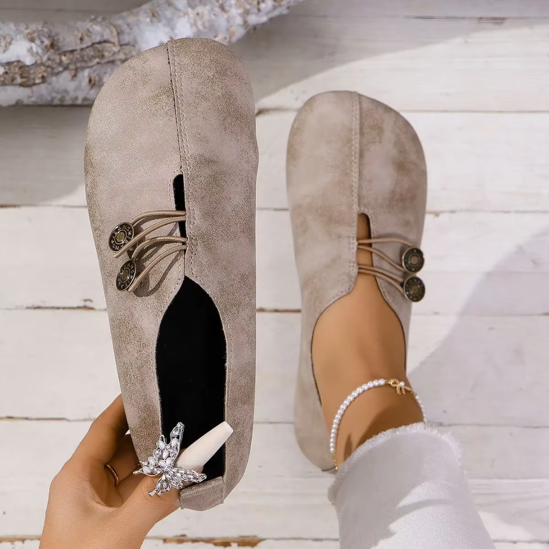 Ballerines Olivia beige tenues à la main, vue de la semelle intérieure et du bouton bronze
