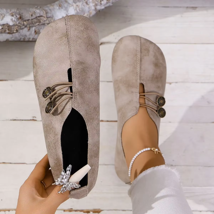 Ballerines Olivia beige tenues à la main, vue de la semelle intérieure et du bouton bronze