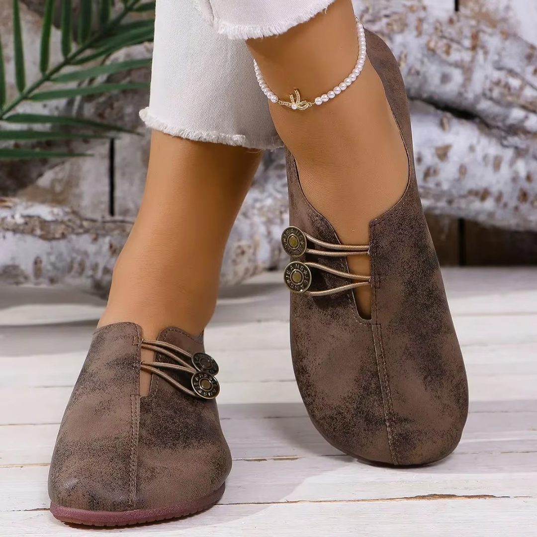 Ballerines Olivia marron foncé posées sur fond bois blanc, vue de profil