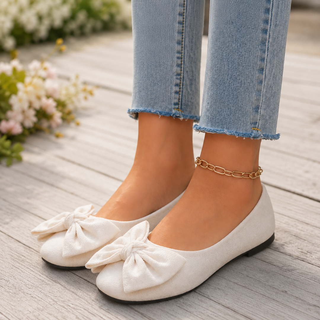 Ballerines femme blanches à noeud, portées sur une terrasse en bois clair