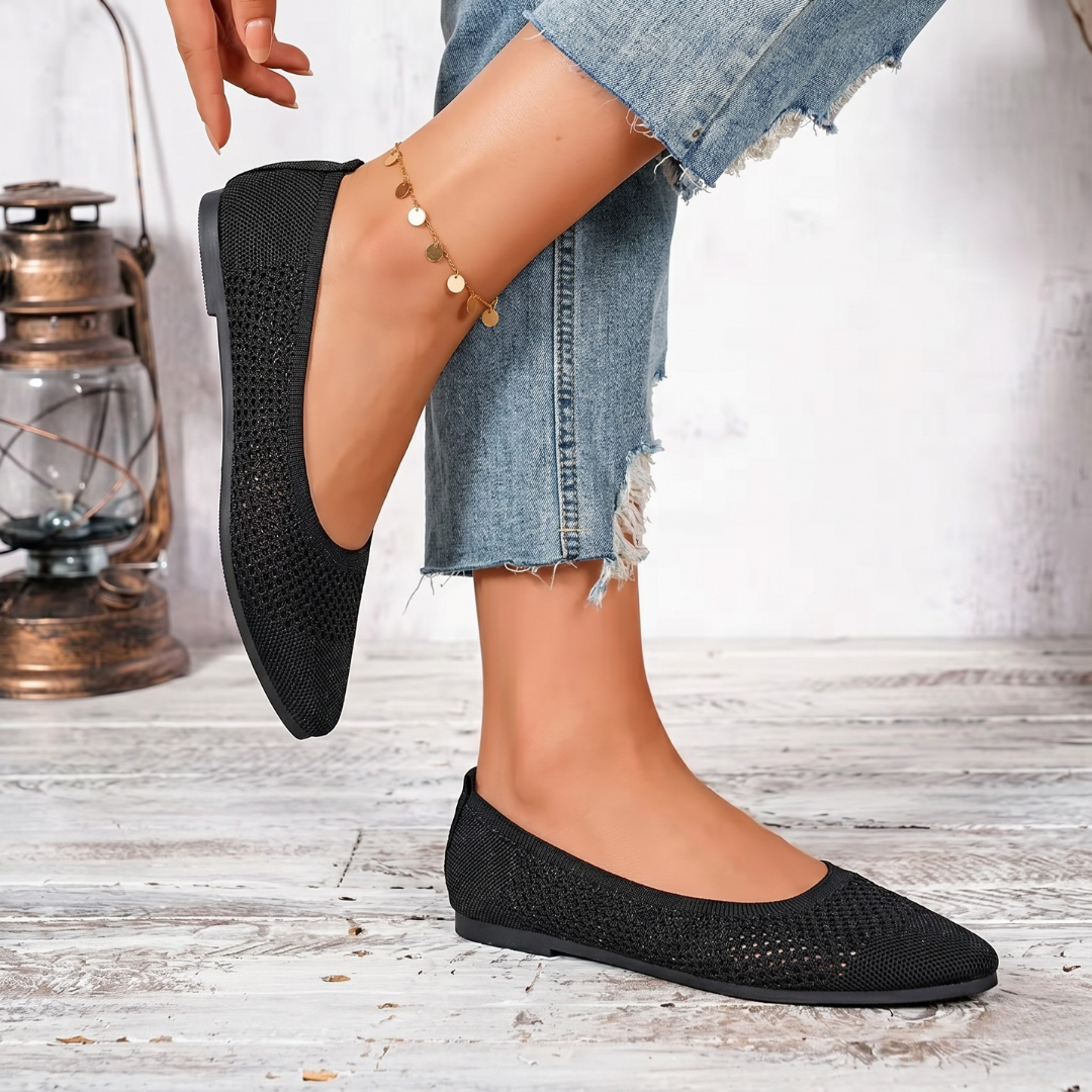Paire de ballerines noires ajourées posées sur surface blanche