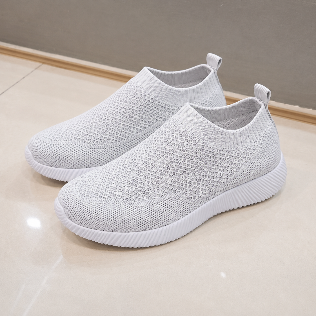 Paire de baskets gris clair posée au sol, semelle blanche souple et légère