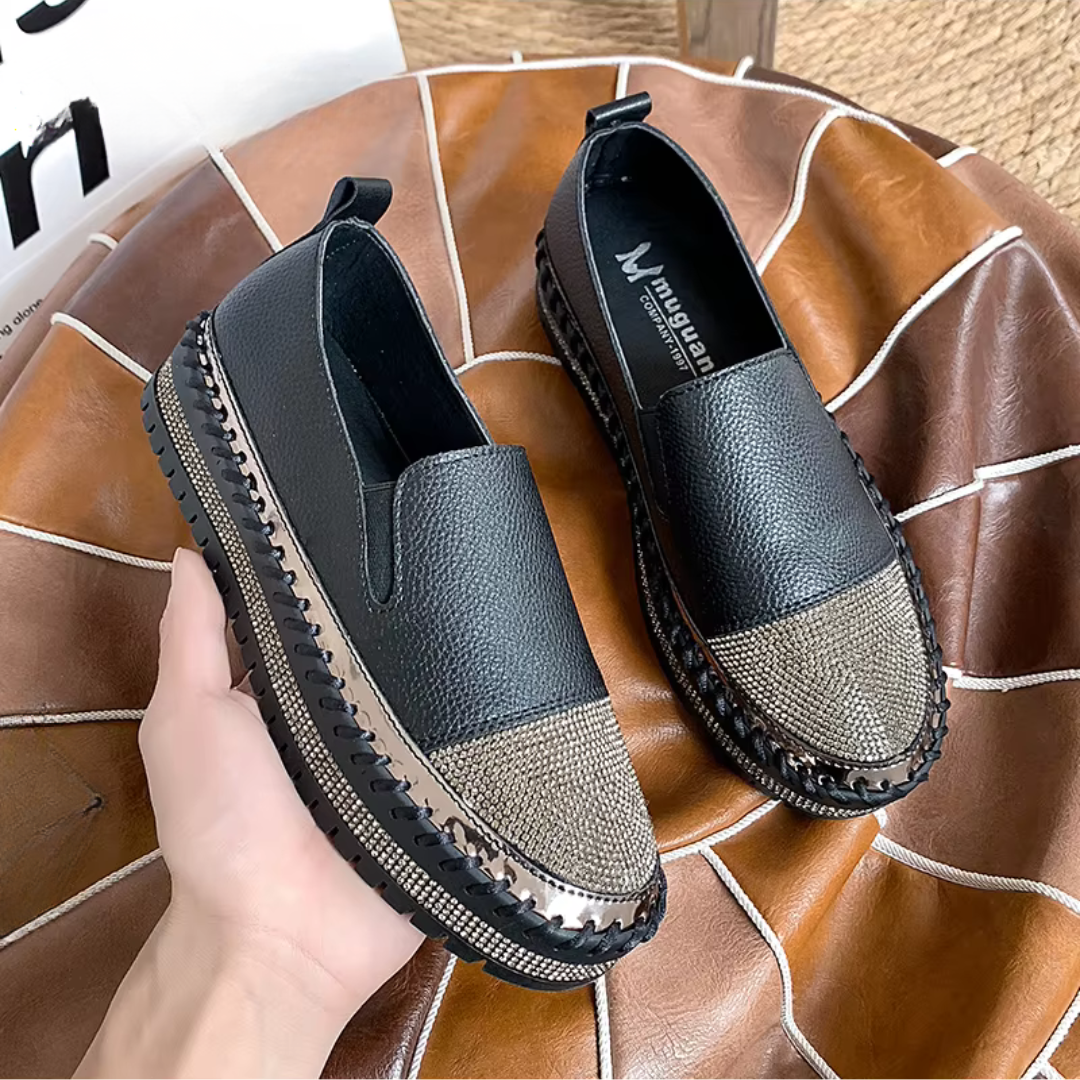 Baskets slip-on noires tenues en main, bout scintillant et semelle crantée épaisse