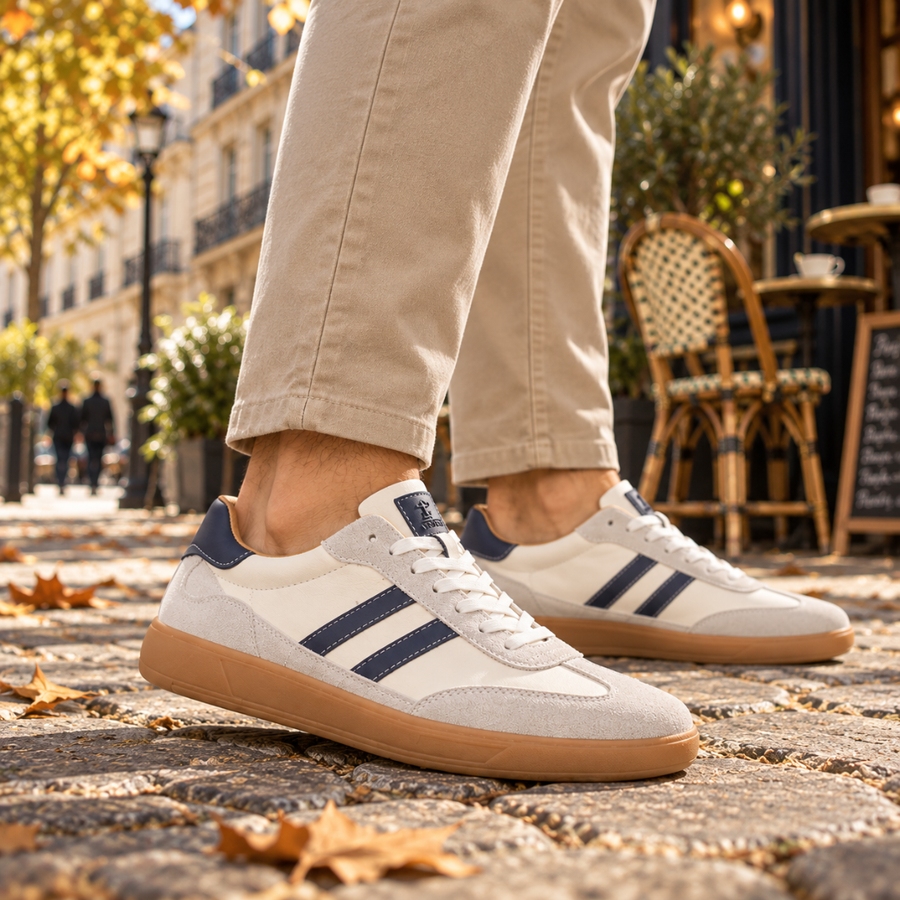 Baskets homme blanches à deux bandes bleu marine et semelle caramel, portées en ville