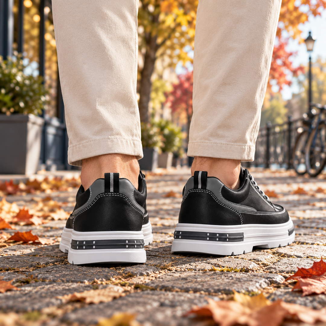 Baskets homme noires portées de dos, semelle blanche crantée sur pavés automnaux