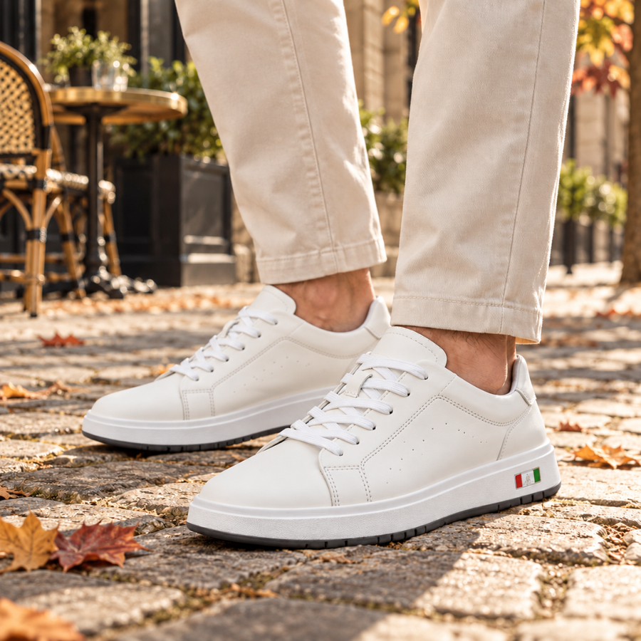 Baskets homme blanches à lacets portées avec un pantalon beige sur pavés