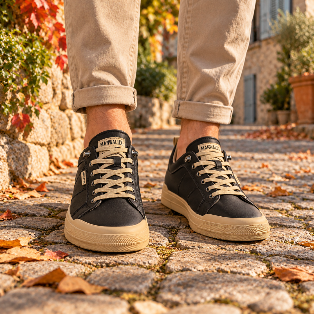 Baskets homme basses noires à lacets clairs et semelle contrastée, portées sur pavés