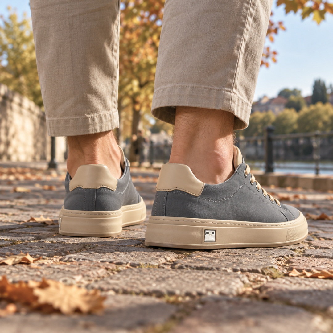 Vue arrière des baskets grises avec talon contrasté beige et plaque métallique latérale