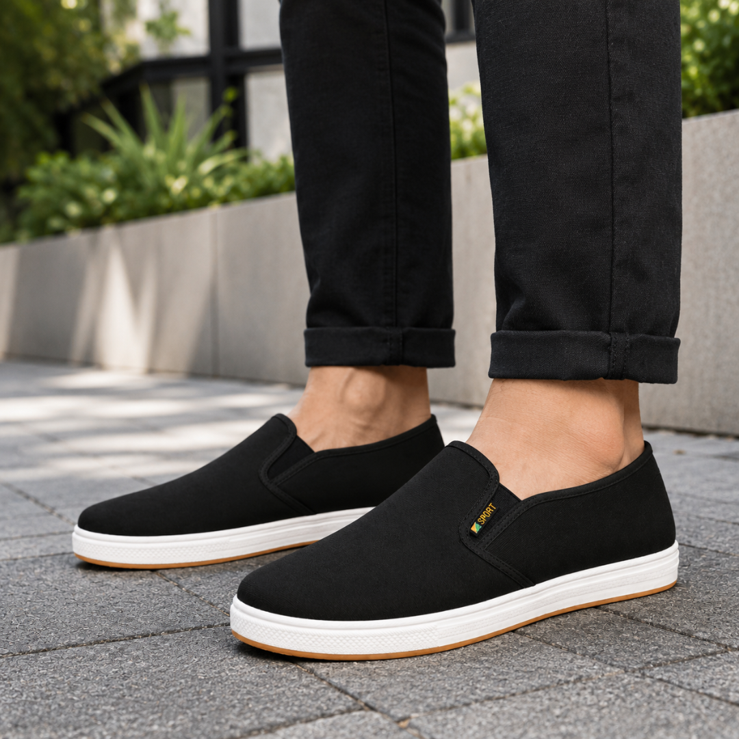 Homme portant des baskets noires avec un pantalon sombre en extérieur