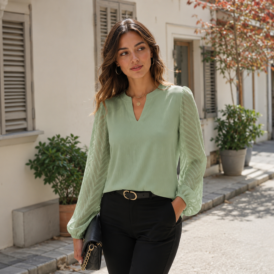 Blouse femme verte à col V fendu portée avec un pantalon noir ceinturé