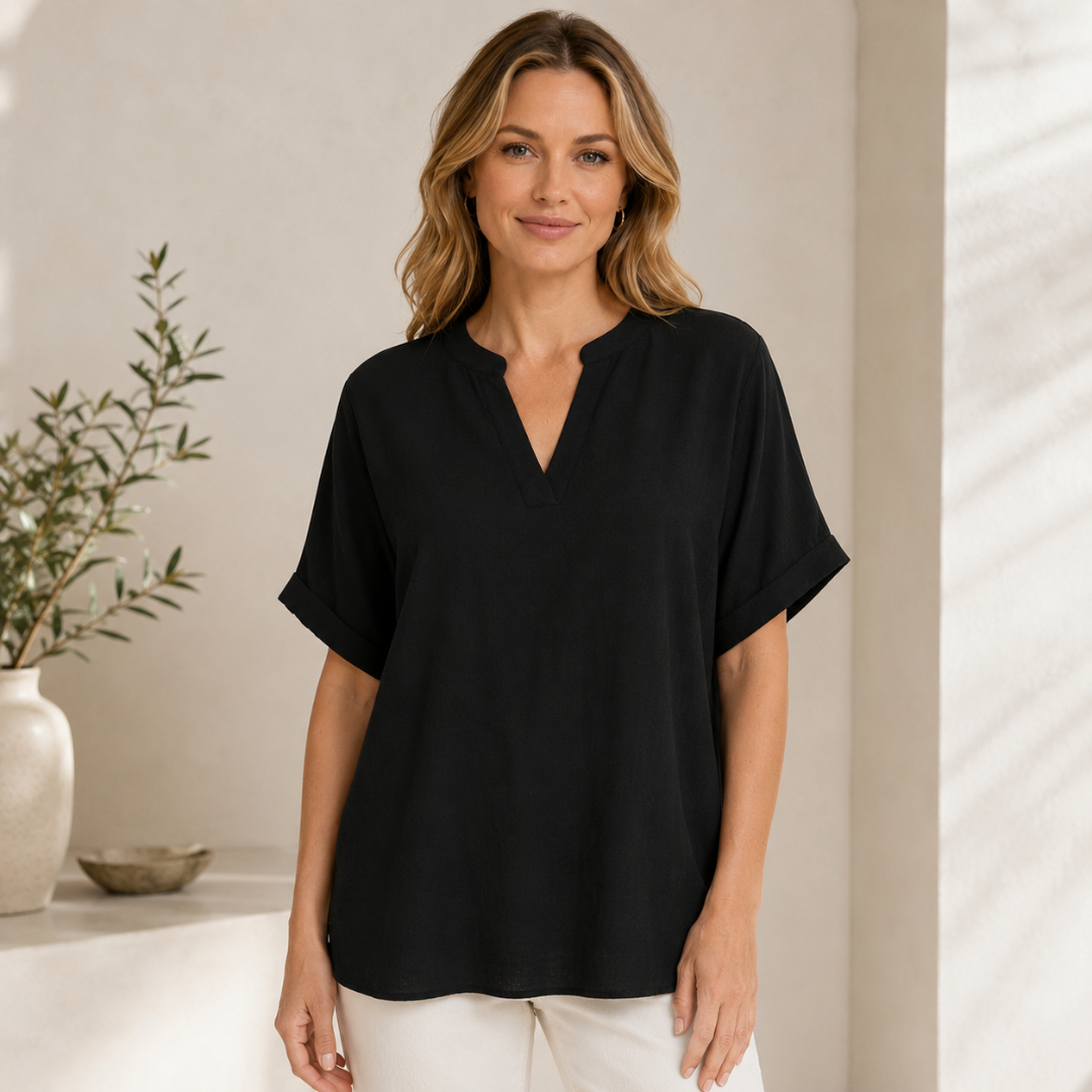 Femme souriante portant une blouse noire à col V, coupe ample