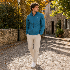 Blouson bleu pétrole ouvert au col, zip intégral visible, associé à un pantalon beige