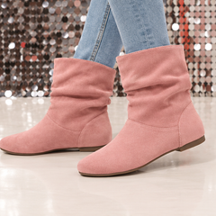 Bottes roses drapées en marche, bout rond et semelle fine visible de profil