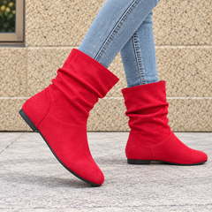 Bottes femme rouges drapées portées avec un pantalon bleu, talon plat et semelle sombre