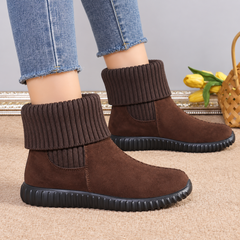 Bottines marron portées avec un pantalon clair, revers tricoté replié sur la cheville