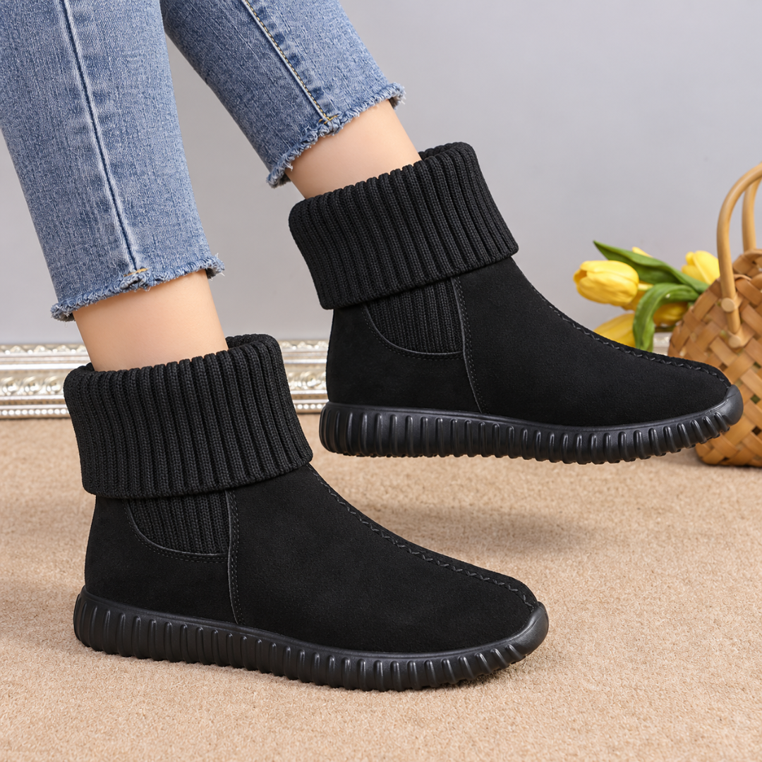 Bottines noires effet daim portées avec un pantalon clair, semelle crantée visible