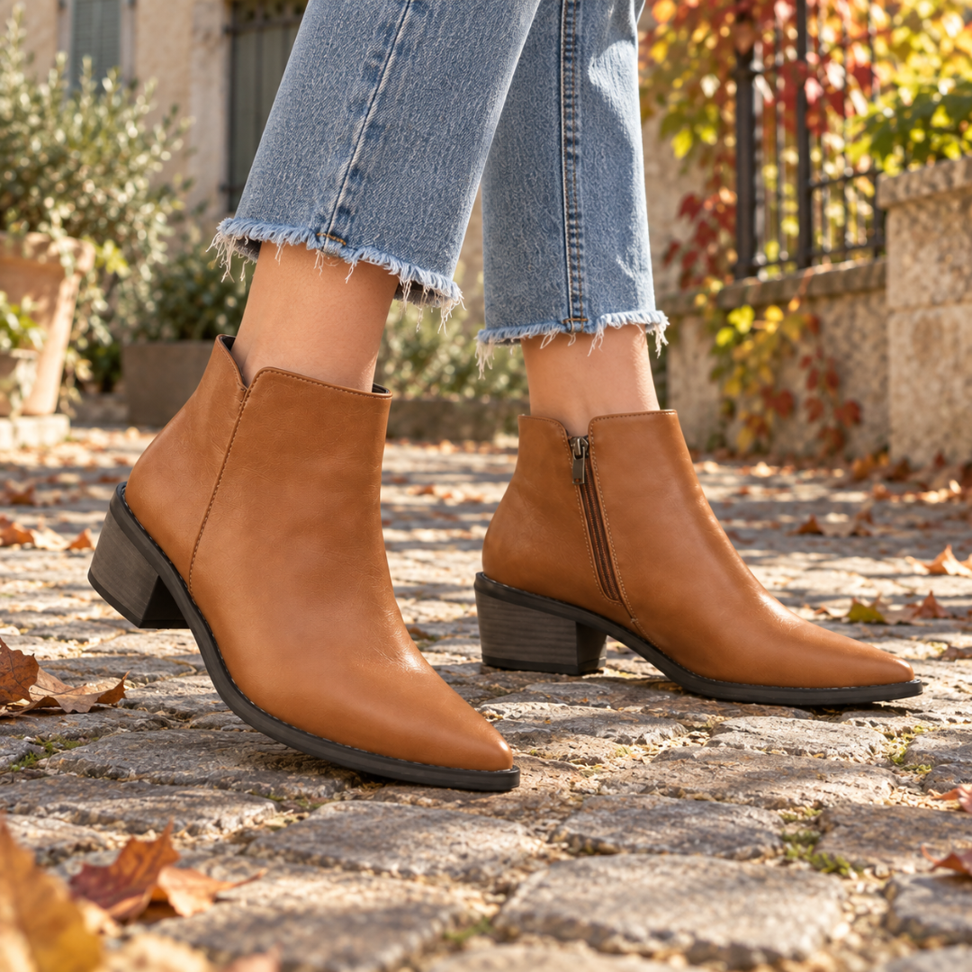 Paire de bottines marron bout pointu sur pavés, liseré sombre le long de la semelle
